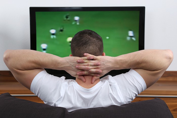 Man in White T-Shirt Watching Football on TV