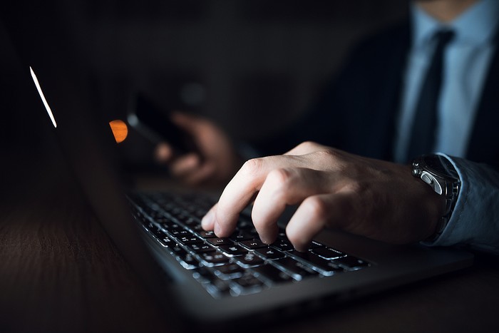 Man in Suit Using Laptop in the Dark