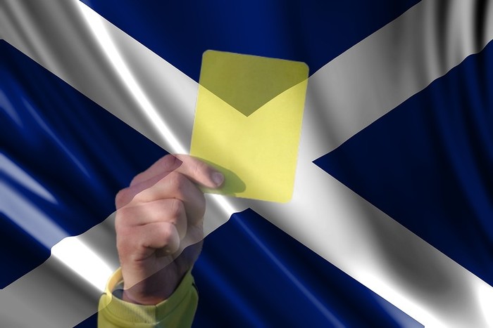 Referee Showing Yellow Card Against Scottish Flag
