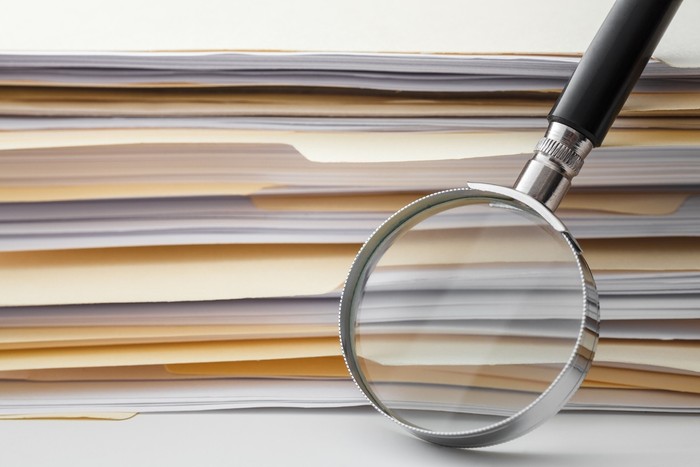 Silver Magnifying Glass Leaning on Stack of Files