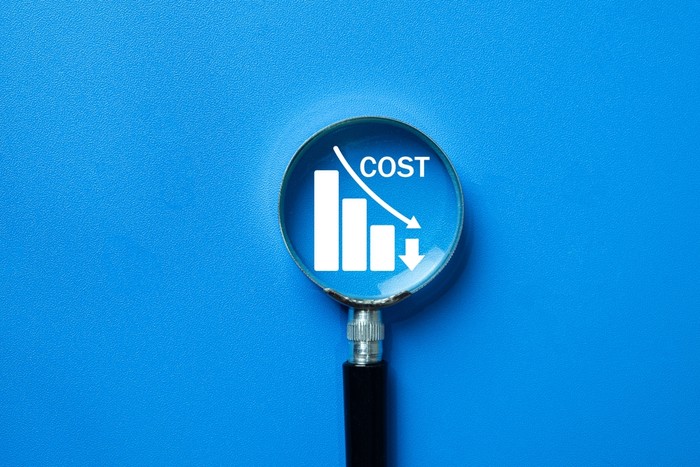 Cost Reduction Chart with Magnifying Glass Against Blue Background
