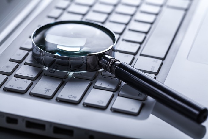 Magnifying Glass Lying on Laptop Keyboard