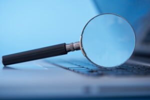 Magnifying Glass on Laptop Against Blue Background