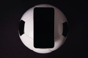 Phone and Football Against Black Background