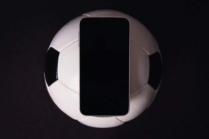 Phone and Football Against Black Background