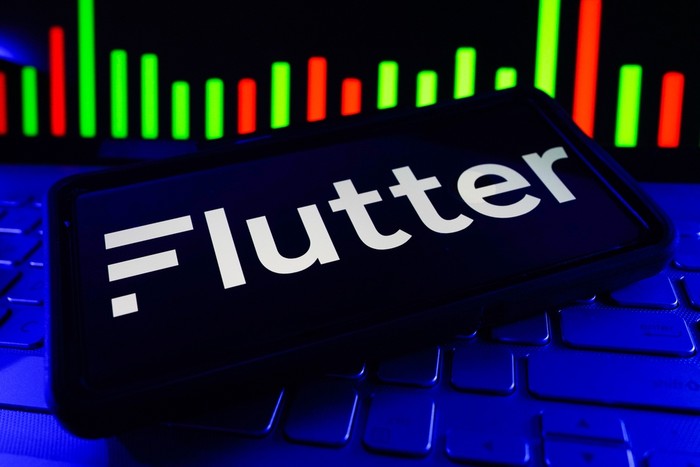 Flutter Logo on Phone Screen Against Stock Market Data