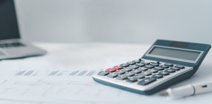 Grey Calculator on Desk with Charts